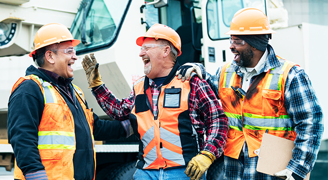 Construction crew in safety gear communicating together at a worksite.